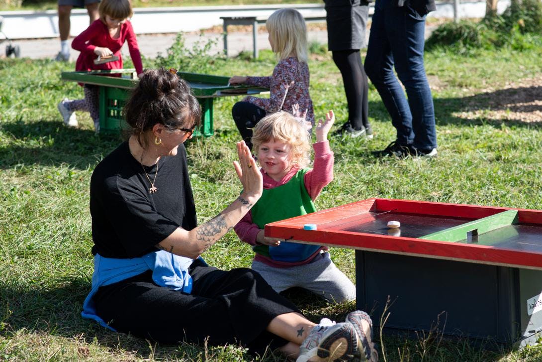 Eine Frau und ein Kind sitzen an einem Spielbrett und machen "high five".